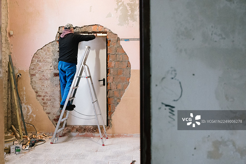 泥瓦匠在现有墙壁上安装新门图片素材