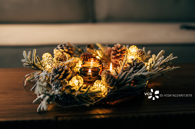 带有四个白色燃烧蜡烛的圣诞花环，以及圣诞球和装饰品，置于木质背景上，营造节日气氛图片素材