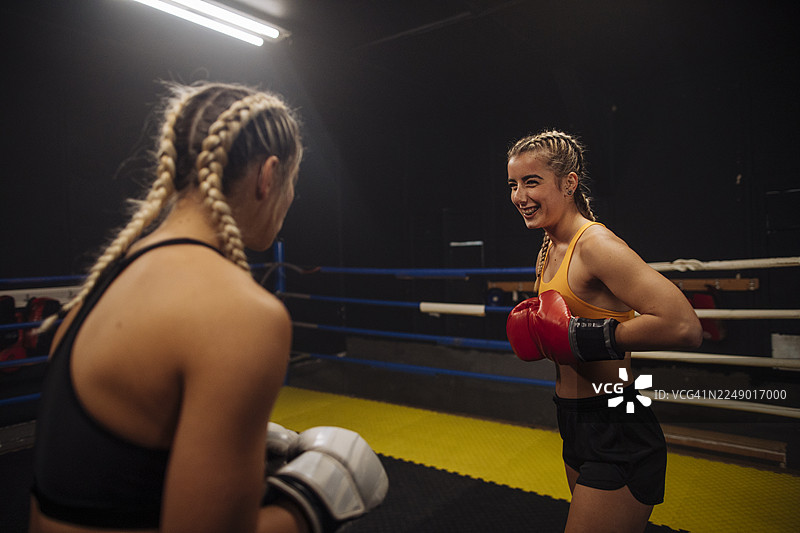 两位女拳击手在健身房的拳击台上进行训练。图片素材
