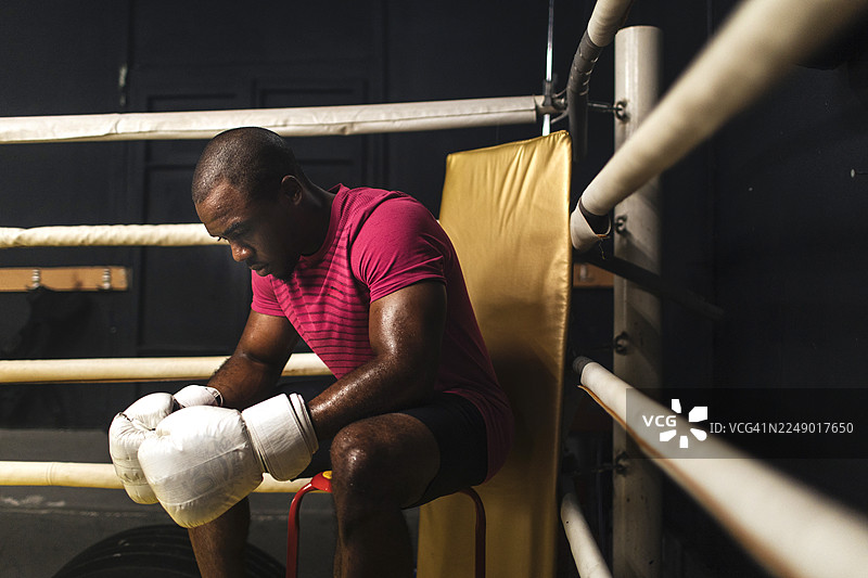 专注的拳击手在训练后在拳击台上休息图片素材