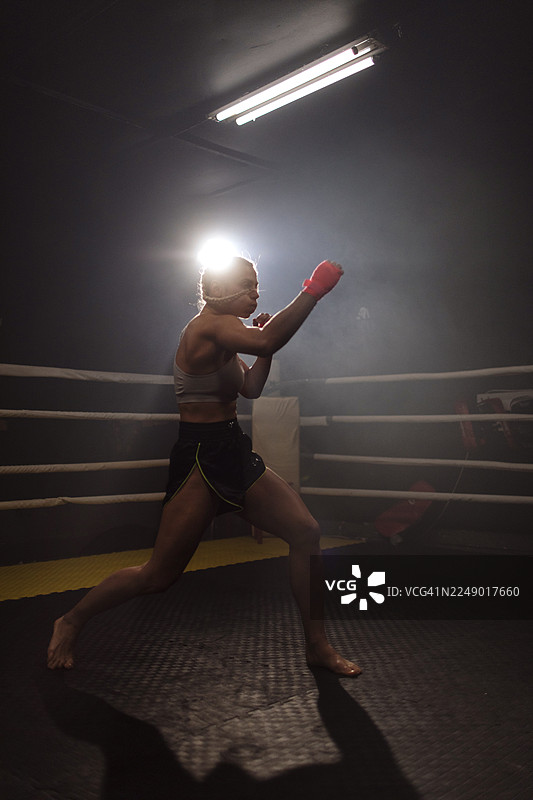 夜间在拳击台上训练的女拳击手图片素材