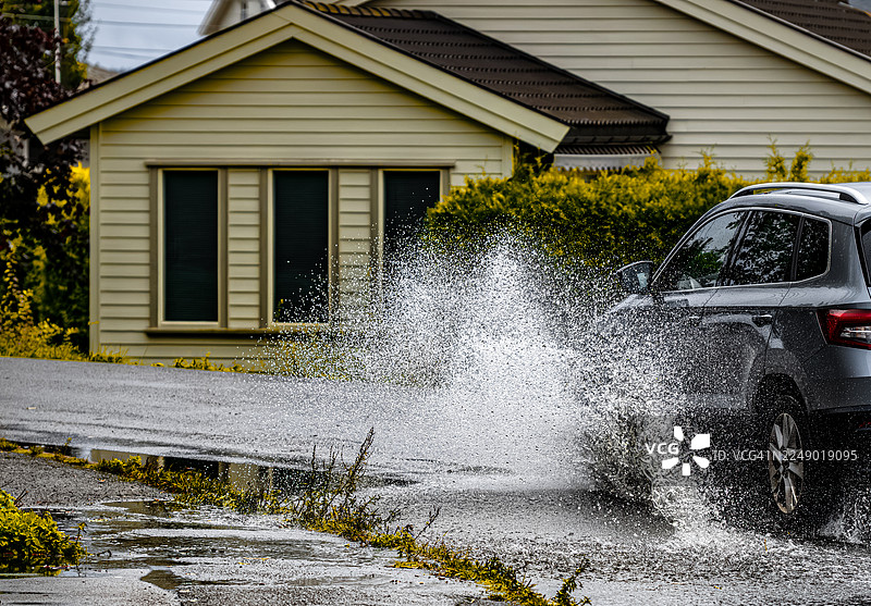飓风过后，道路上的大水坑飞溅，幸运的是人行道上没有人图片素材