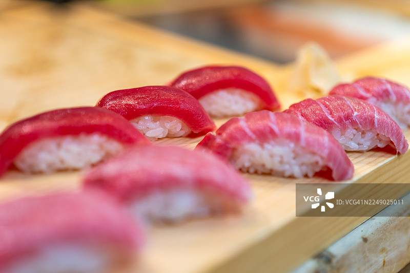 新鲜的金枪鱼寿司饭团摆放在木板上，准备上桌。图片素材