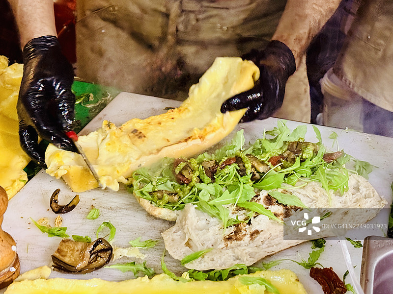 街头食品摊贩正在制作帕努佐，配有拉克莱特奶酪、意式培根和松露图片素材