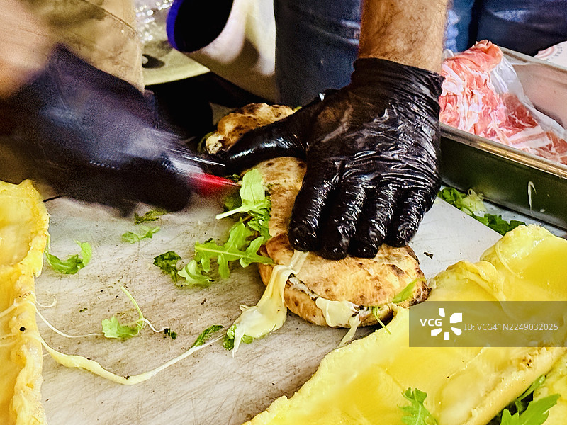 街头食品摊贩制作帕努佐，配以拉克雷特奶酪、意式培根和松露图片素材