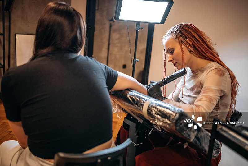 女纹身师正在为顾客的手臂纹身图片素材