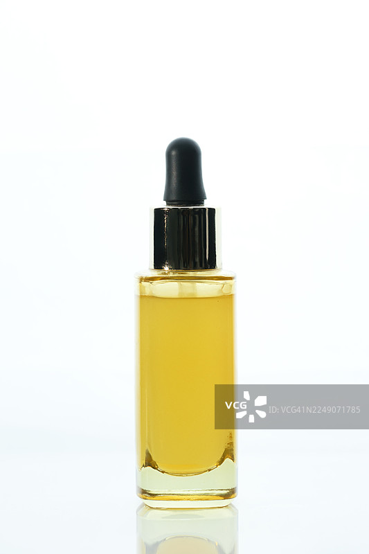白色背景上的金色护肤精华滴管瓶，优雅的化妆品油容器，用于美容、奢华包装和健康产品摄影图片素材