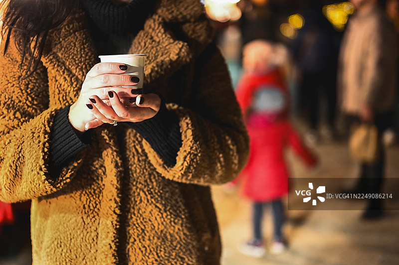 女人在冬季圣诞集市上拿着热饮图片素材
