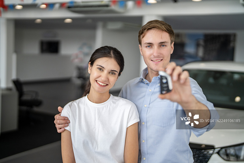 一对快乐的夫妇在汽车经销商处展示新车钥匙图片素材