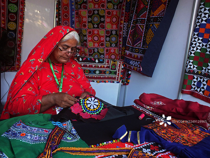 一位年长的女士正在忙碌地制作信德族纺织品/手工艺品图片素材