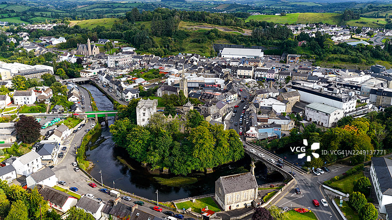 从空中俯瞰多尼戈尔镇中心，这里有历史悠久的石头建筑、教堂塔楼以及贯穿小镇的埃斯克河，四周环绕着爱尔兰西北部多尼戈尔郡郁郁葱葱的绿色山丘，展现了城市遗产和旅游目的地的概念。图片素材