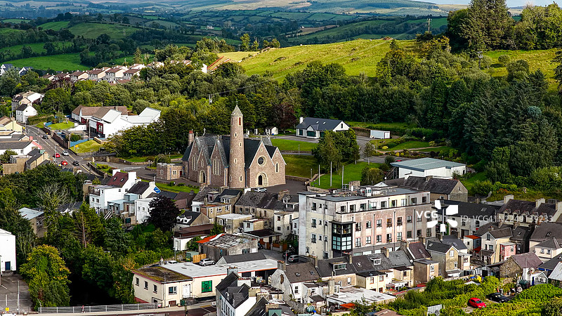 爱尔兰多尼戈尔镇圣帕特里克罗马天主教堂的航拍图，周围环绕着色彩缤纷的房屋、郁郁葱葱的爱尔兰乡村和远处的山丘，展现了爱尔兰西北部历史悠久的教堂建筑和文化旅行的概念。图片素材