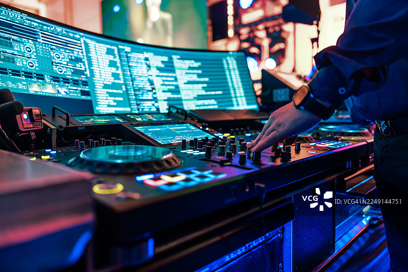 DJ的手部特写，正在精心调试大型混音台上的控制按钮。图片素材