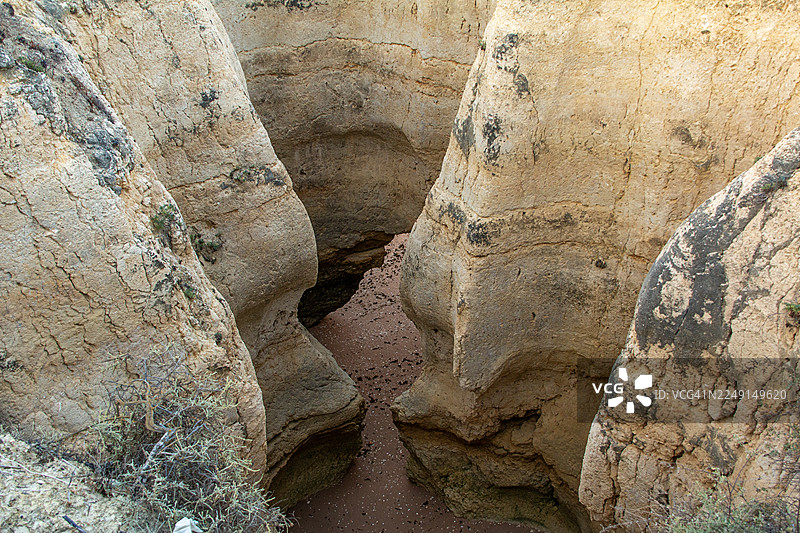 早晨的阳光洒在海岸悬崖上，展示了葡萄牙阿尔布菲拉卡斯泰洛海滩的岩石构造和天然海蚀洞。图片素材