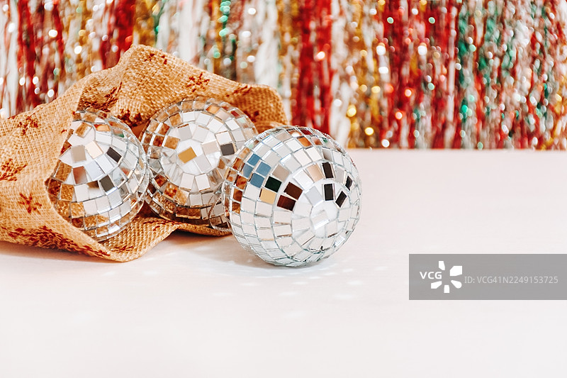 三个闪亮的迪斯科球从包里滚出，放在白色表面上，灯光明亮图片素材