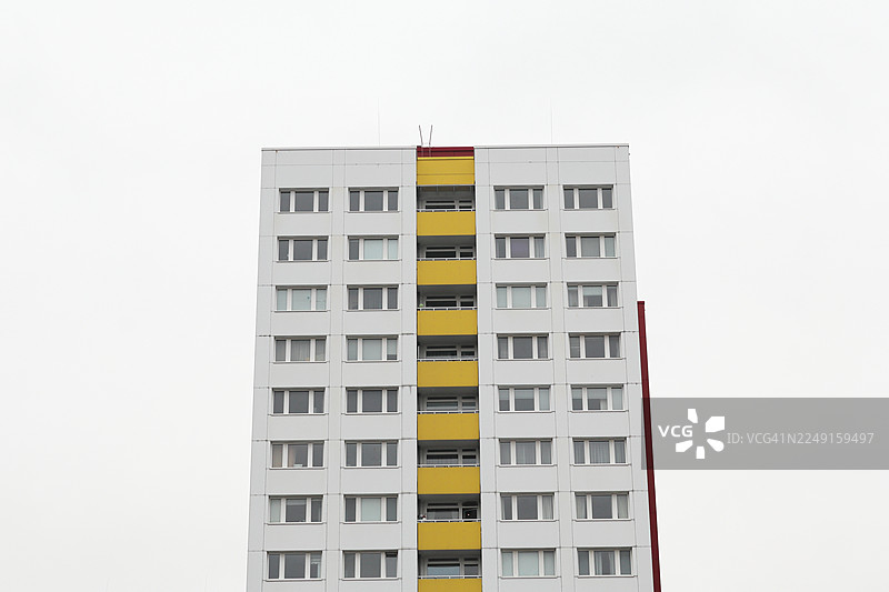 居中的广角照片，捕捉了一个预制混凝土板建筑（德语中常称为Plattenbau）的上部区域图片素材