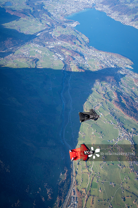 翼装飞行员翱翔于湖泊与群山之上图片素材