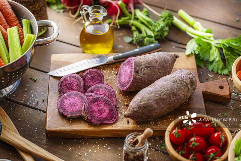 新鲜的有机紫薯、蔬菜和砧板。健康均衡素食餐的食材。根茎类蔬菜或膳食纤维图片素材