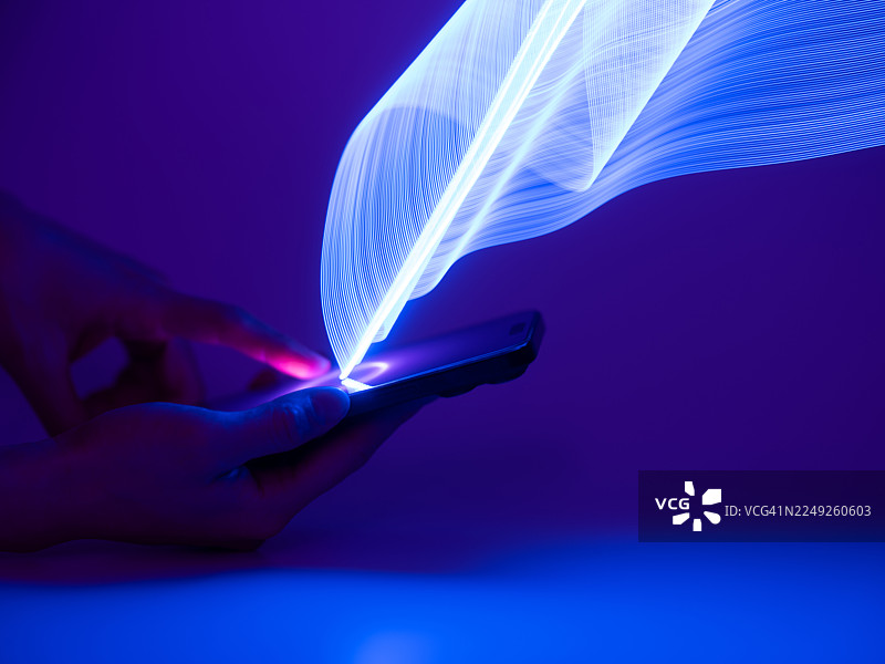 手持智能手机的特写。长曝光和LED光绘。科技与人工智能概念。图片素材