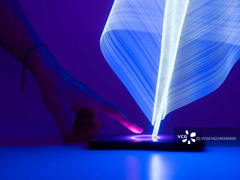 特写一只手触摸智能手机屏幕。采用长曝光和LED灯光绘画技术，概念涉及科技与人工智能。图片素材