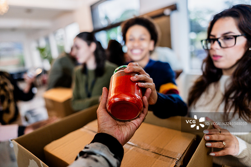 捐赠活动中，志愿者传递罐头食品的特写图片素材