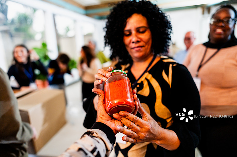 捐赠活动中，志愿者递交罐头食品的特写图片素材