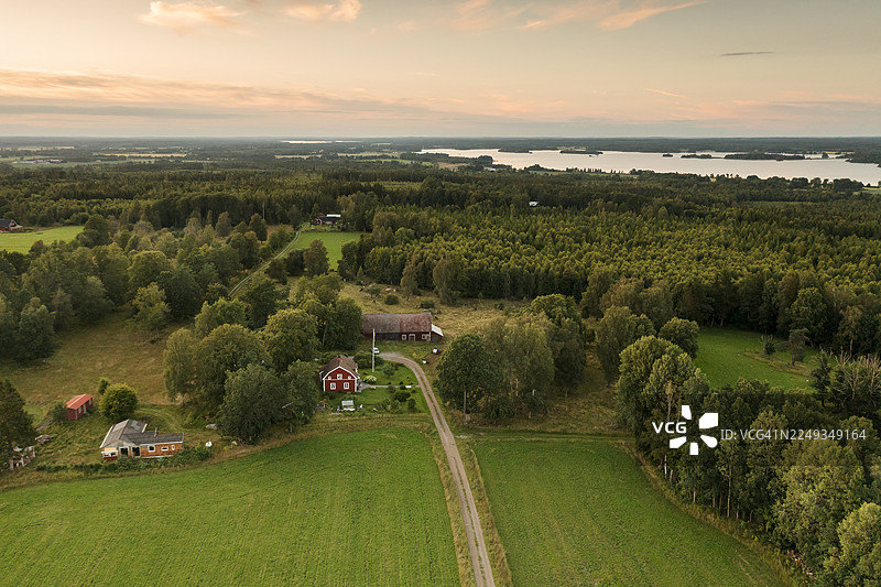 俯瞰乡村地区，有森林、田野、草地和一个红色的住宅建筑。图片素材