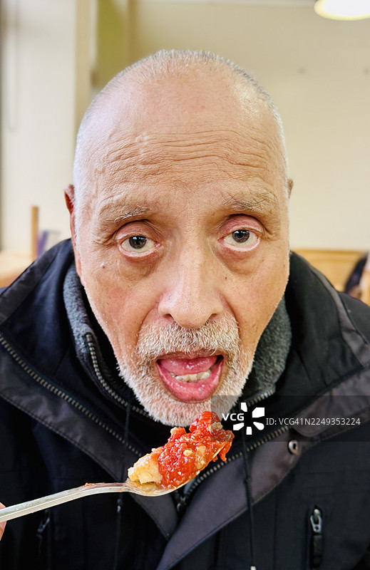 一位老人正在用叉子吃东西图片素材