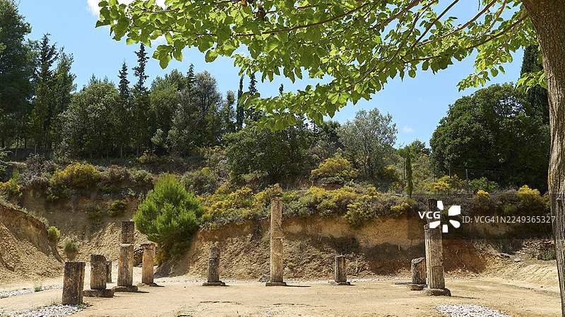 古希腊尼米亚古体育场遗址，位于伯罗奔尼撒半岛，周围环绕着郁郁葱葱的绿色景观，天空中布满云彩。图片素材