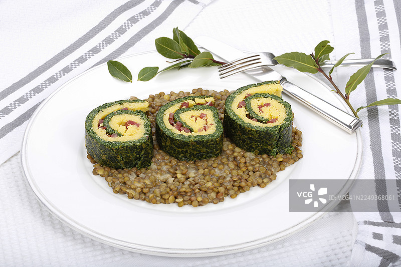 德国南部美食,玉米糊菠菜卷配阿尔布塔扁豆,盛放在餐盘上,配有月桂叶、扁豆蔬菜、熏肉、培根丁,健康,美食摄影,摄影棚,德国图片素材
