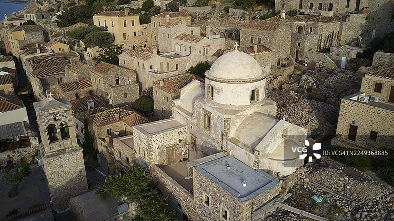 无人机视角，传统村庄植被环绕的教堂和石头房屋的鸟瞰图，莫奈姆瓦夏，莫奈姆瓦西亚，马尔瓦西亚，拜占庭小镇，岩石岛，堡垒，拉科尼亚，伯罗奔尼撒，半岛，希腊图片素材