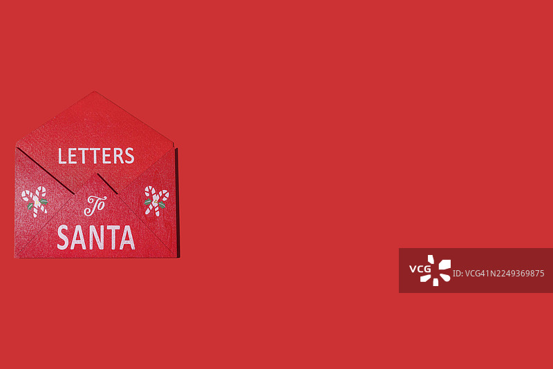 红色的木制圣诞老人信件收纳盒，位于左侧，背景为红色。圣诞节、节日、装饰、庆祝、礼物、祝福和圣诞老人。图片素材