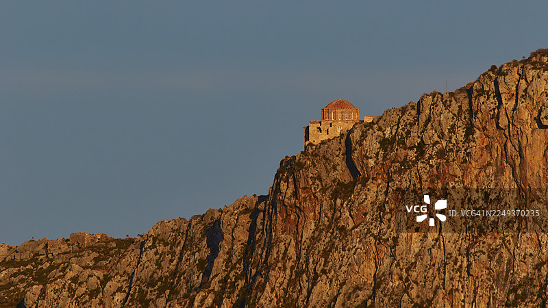 圣索菲亚东正教教堂,一座高耸于岩石上的小教堂,在橙色的晚霞中被照亮,莫奈姆瓦夏,马尔瓦西亚,拜占庭小镇,岩石岛,堡垒,拉科尼亚,伯罗奔尼撒,半岛,希腊图片素材