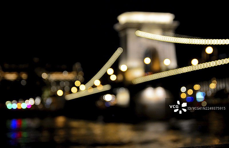 夜晚，模糊的光线勾勒出匈牙利布达佩斯链子桥的轮廓，倒映在多瑙河中，营造出梦幻般的氛围。图片素材