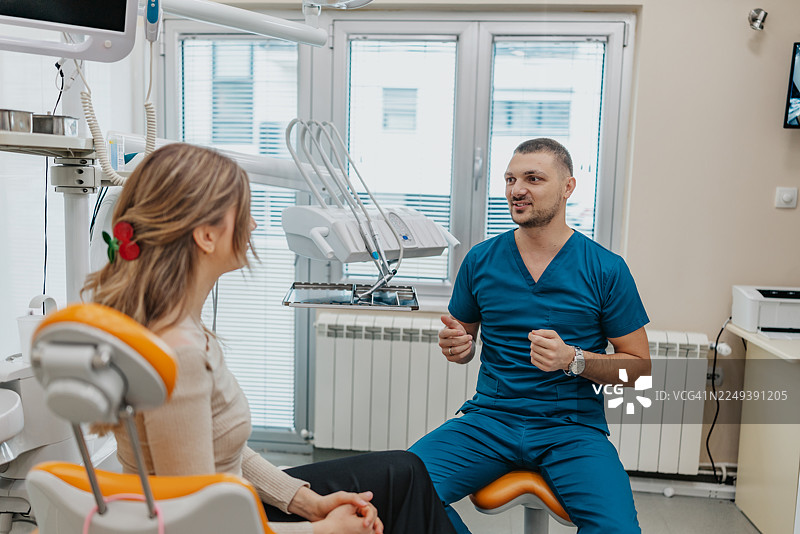 牙医在现代牙科诊所为患者提供咨询，讨论治疗方案和程序图片素材