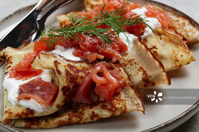 美味的薄饼，配三文鱼和酸奶油，早餐，盛在盘子里，乡村风格，配有餐具图片素材