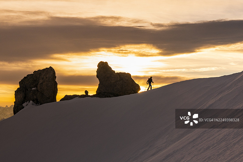 日出时，登山者正在攀登雪山山脊图片素材
