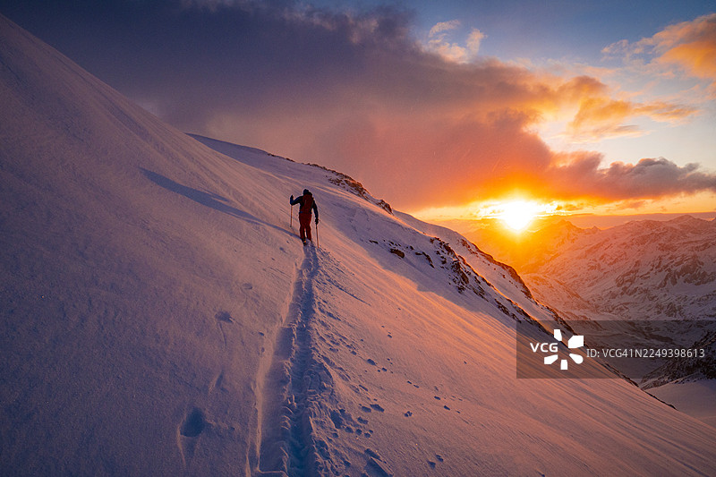 黎明时分，滑雪登山者在雪山山脊上图片素材