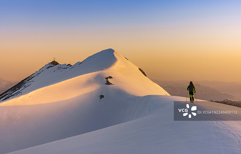 日出时，登山者正在攀登雪山山脊图片素材