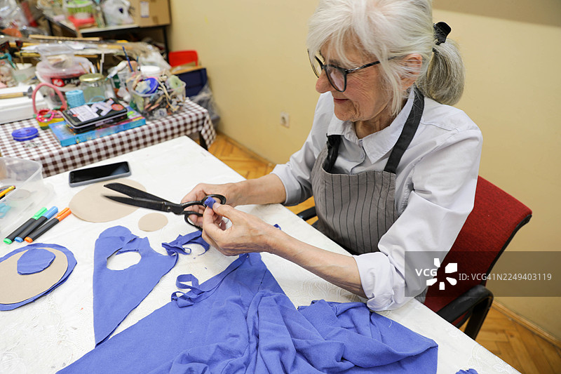 老妇人的双手正在修剪纺织品和纸张图案图片素材