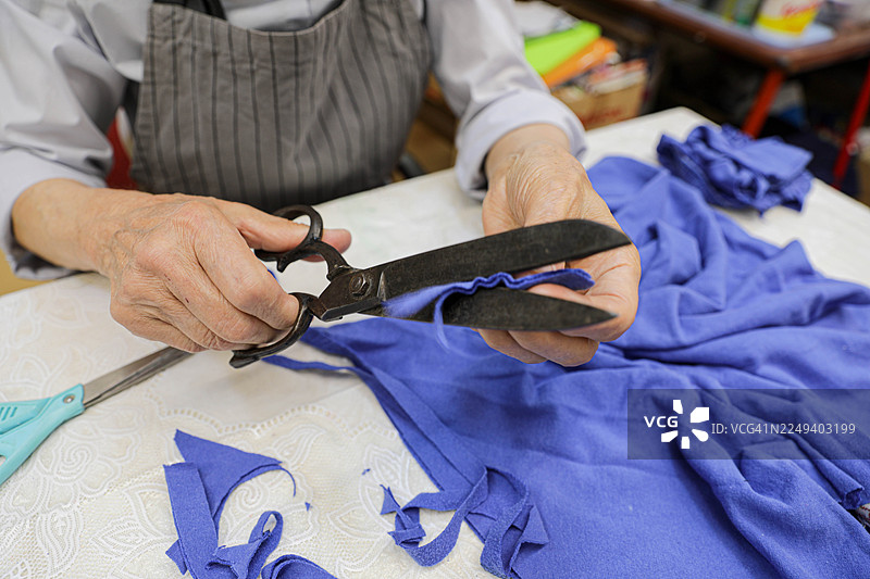 老妇人正在修剪纺织品和纸张图案的双手图片素材