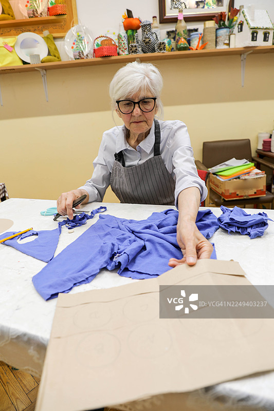 老妇人修剪纺织品和纸样图片素材