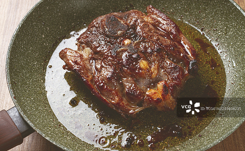 煎牛排，带骨小牛肉颈肉，煎锅烹饪肉类，俯视，无人图片素材