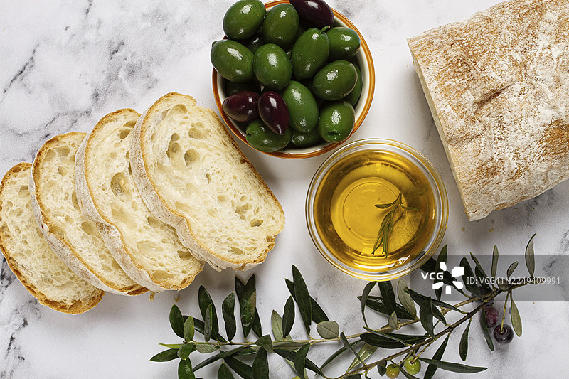 开胃菜，切片恰巴塔面包，配橄榄油、绿橄榄、哈尔基迪基橄榄、经典绿橄榄，大理石桌上，俯视图，无人图片素材