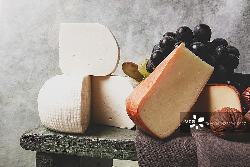 格鲁吉亚奶酪，包括伊梅列季奶酪和烟熏苏鲁古尼奶酪，搭配葡萄和坚果，摆放在砧板上，展现格鲁吉亚美食，无人像图片素材
