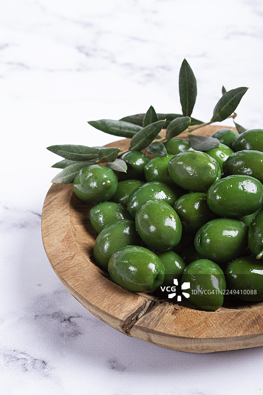 哈尔基迪基橄榄，经典的希腊绿橄榄，盛放在木碗中，置于大理石桌上，无人像图片素材