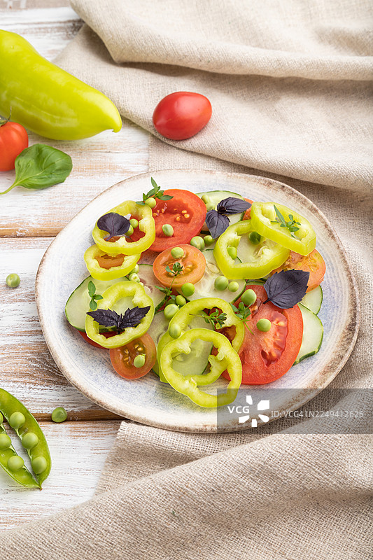 素食沙拉，由青豆、番茄、辣椒和罗勒制成，置于白色木质背景和亚麻布上。俯视，特写。图片素材