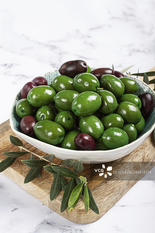 一个碗里的哈尔基迪基橄榄，经典的希腊绿橄榄，放在一块砧板上，俯视视角，无人图片素材