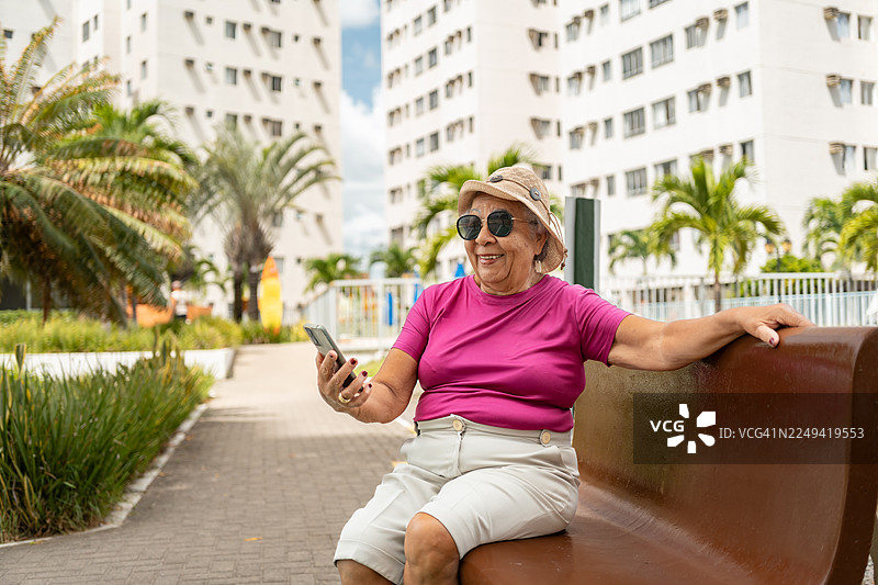 一位年长的女性在公寓里使用智能手机图片素材