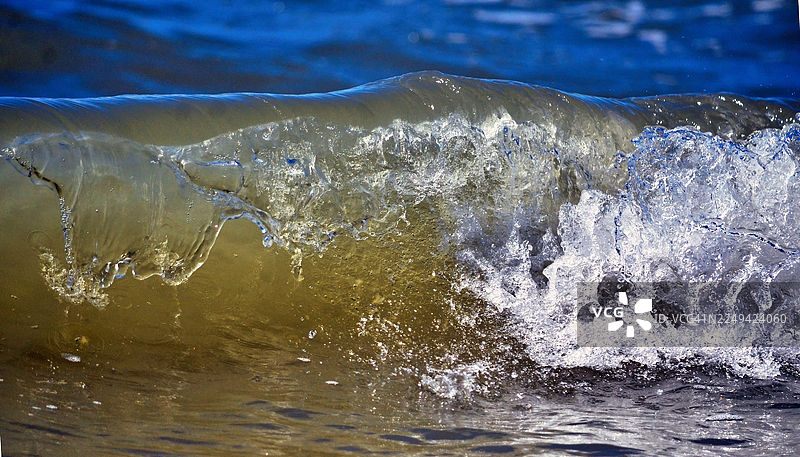 充满力量的巨浪拍打，溅起白色泡沫，蓝色海水在动态特写中展现图片素材